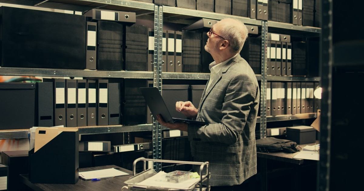senior-businessman-holding-laptop-in-a-warehouse
